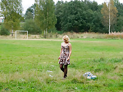 Blonde girl takes a leak in the middle of a field